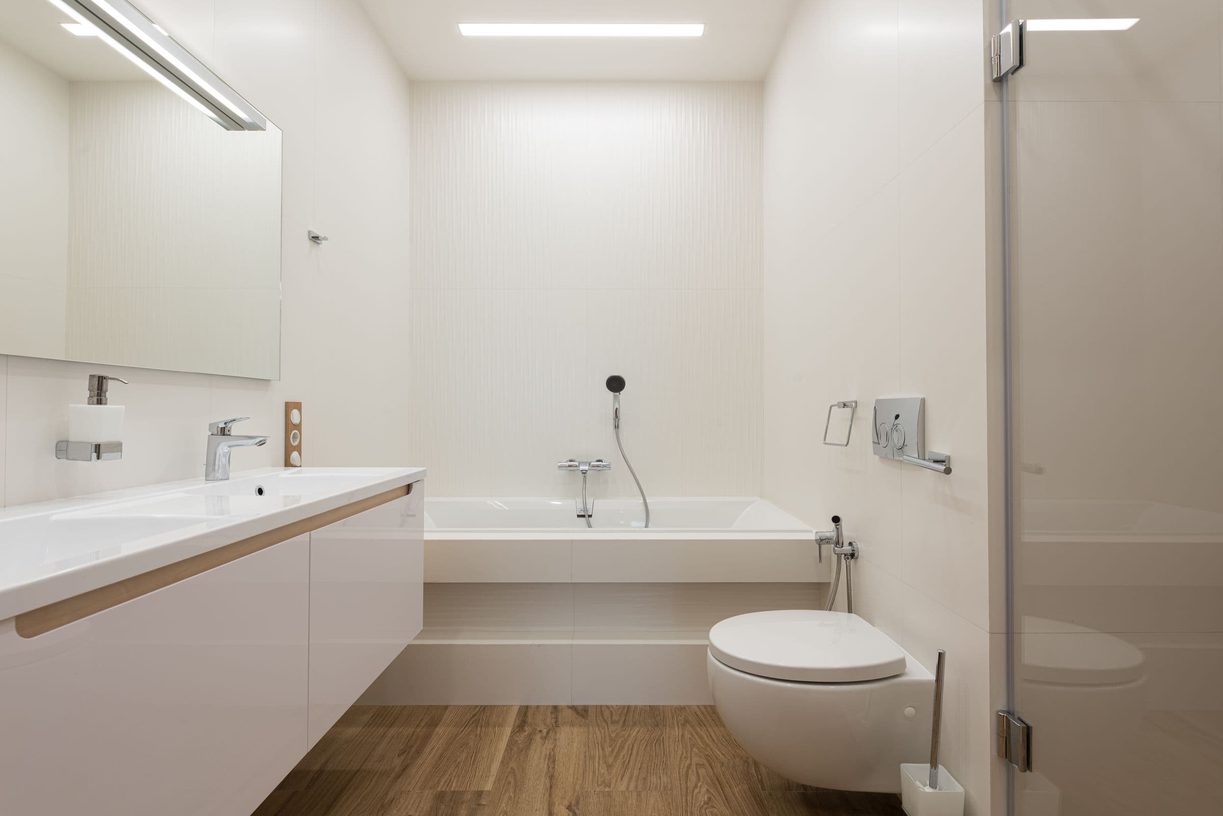 Weißes Bad mit Badewanne und Holzboden