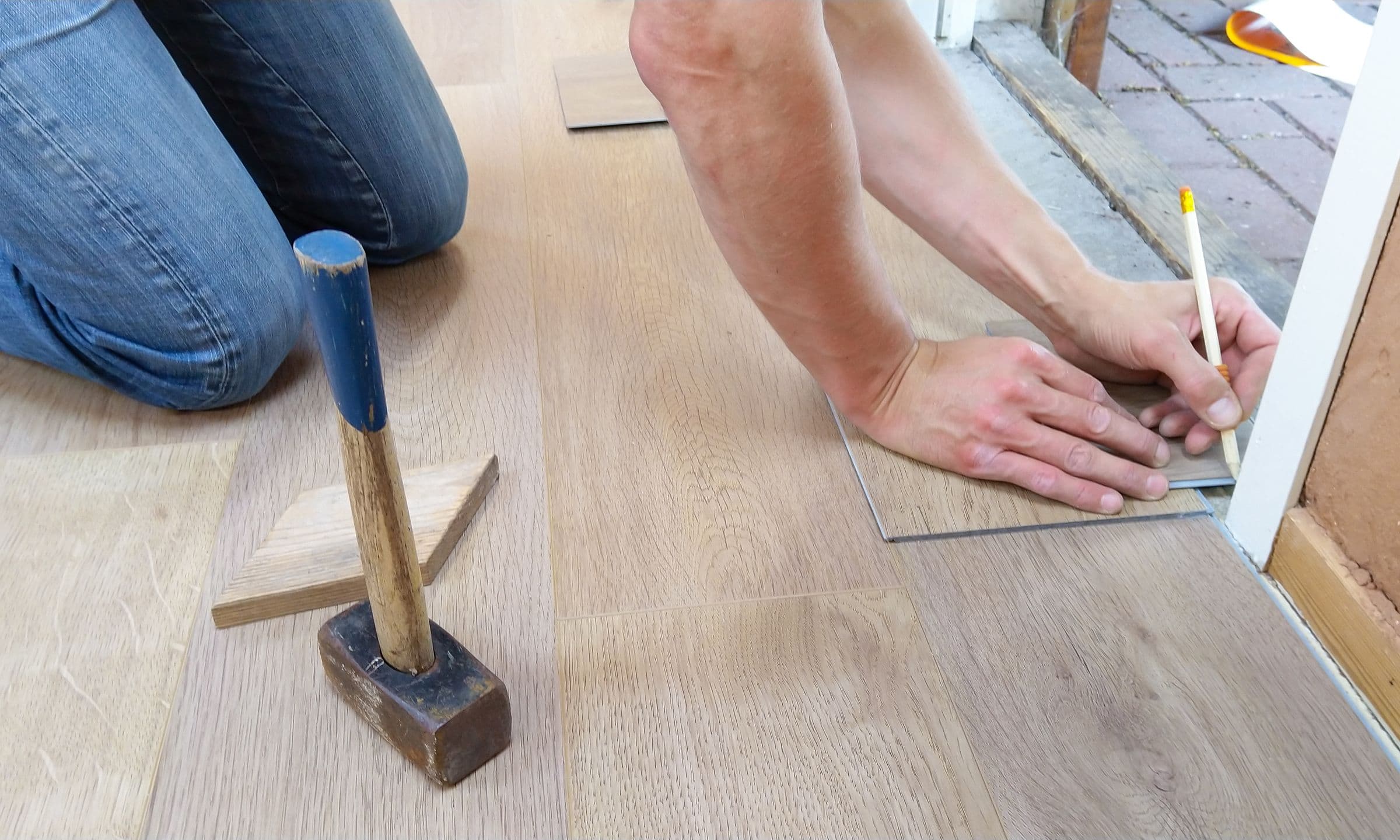 Verlegen eines Holzbodens mit Bleistift und Hammer