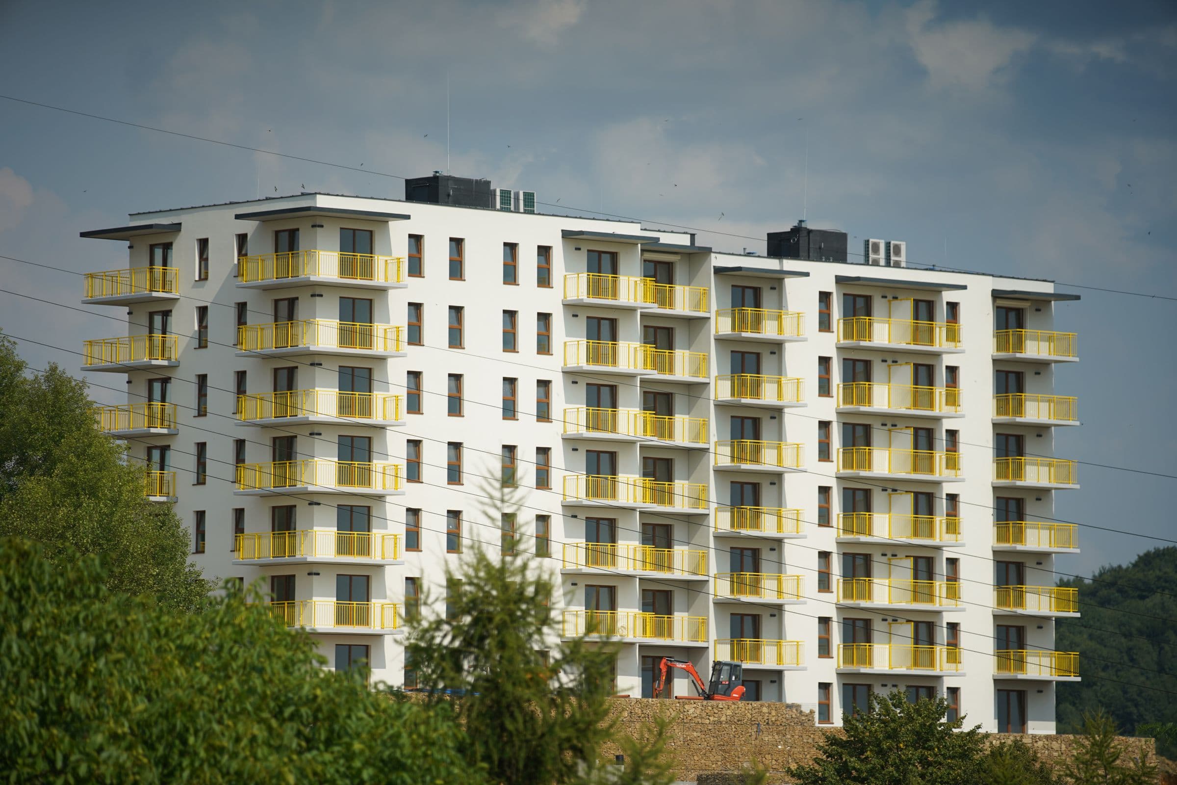 Wohngebäude mit hellen Balkonen hinter Bäumen