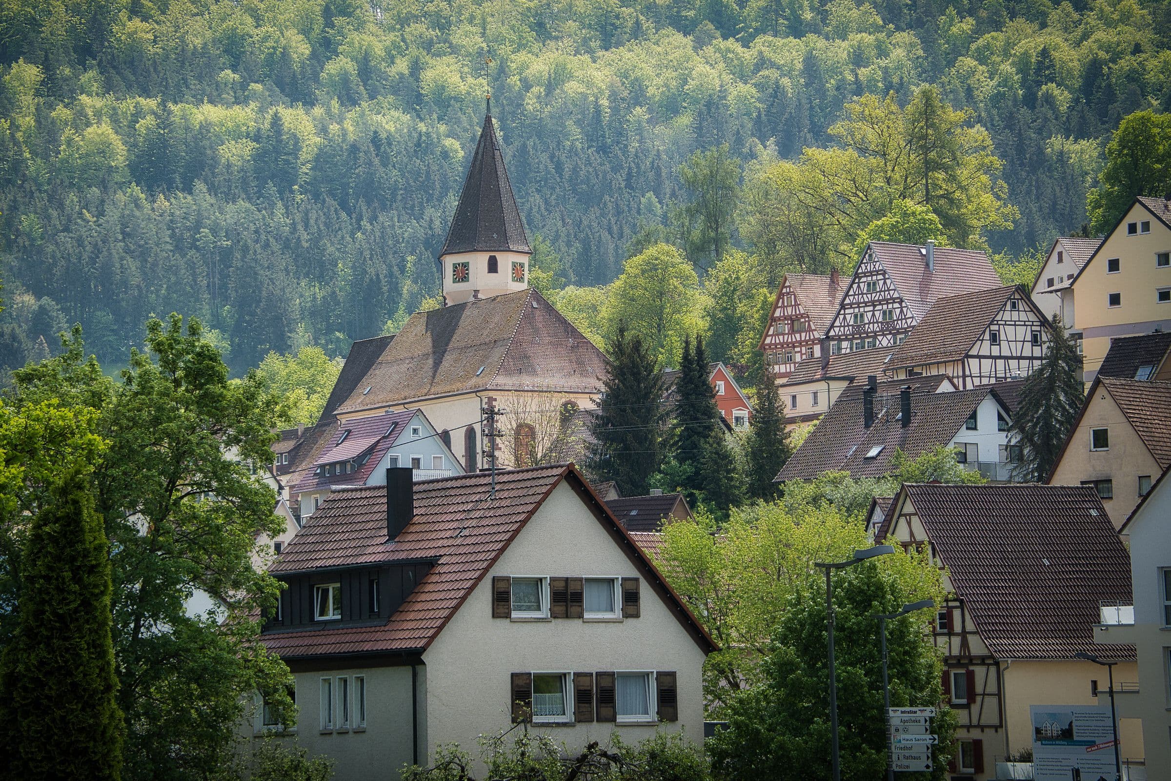 Kleinstadt mit Kirchturm zwischen bewaldeten Hügeln
